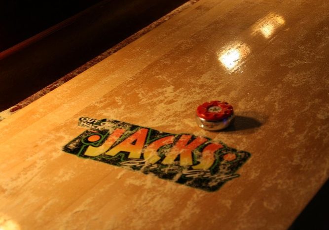 A shuffleboard table with the word jacks on it.